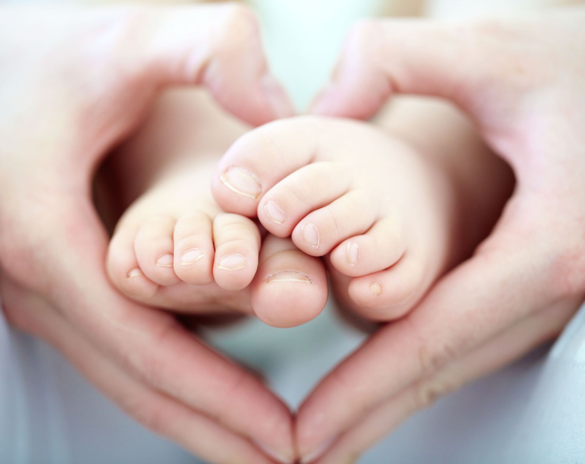 Manos en forma de corazón sosteniendo los pies de su hijo