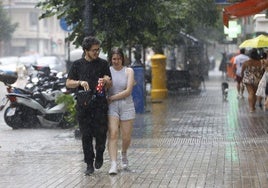 Dos personas se refugian de la lluvia este sábado.