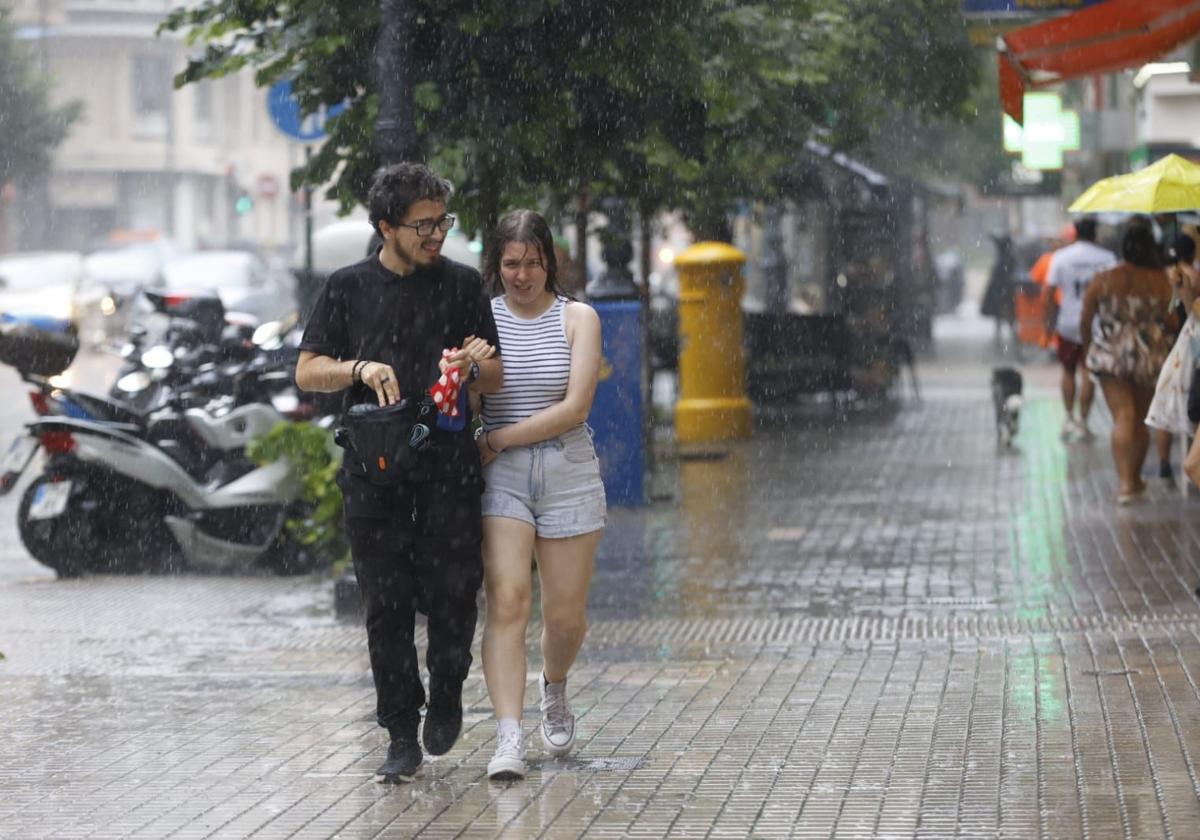 Dos personas se refugian de la lluvia este sábado.