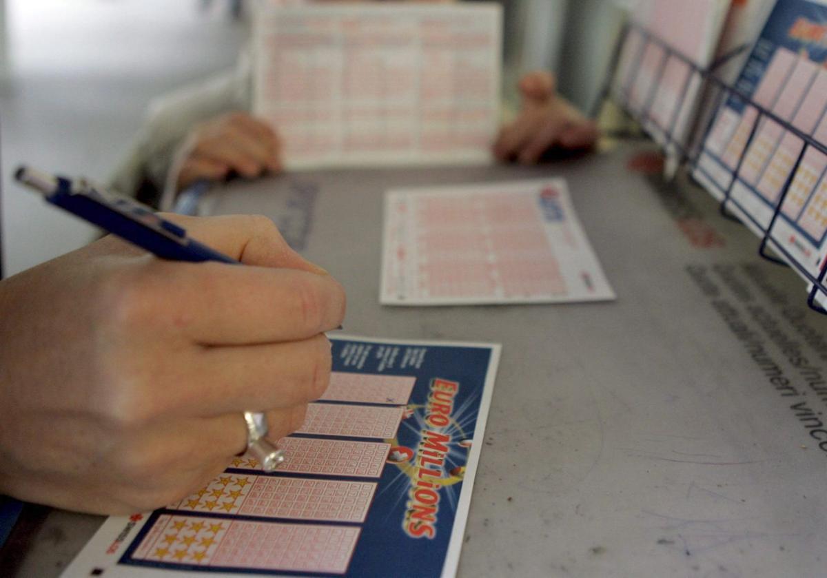 Una mujer rellena un boleto de Euromillones en un despacho de lotería.