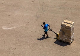 Un trabajador transporta varias cajas bajo el sol.