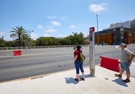 Dos usuarios en la parada de la EMT en medio del puente de Campanar que apenas tiene sombra.
