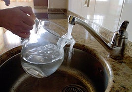 Una mujer llena una jarra de agua.