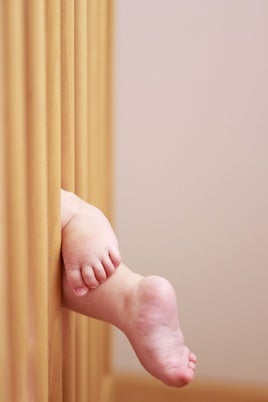 Pies de un bebé colgando de la cuna