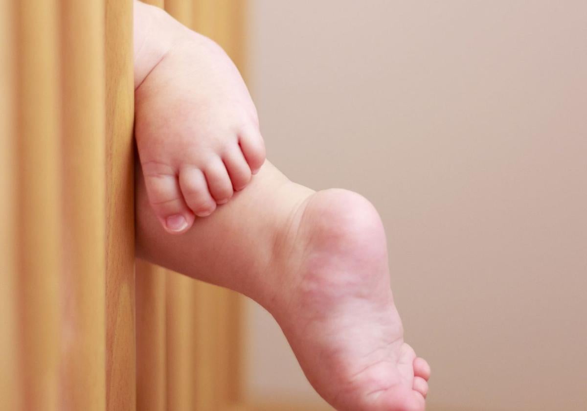 Pies de un bebé colgando de la cuna