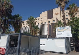 Cartel con el anuncio de la obra junto al barracón en el hospital Peset.
