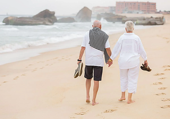 Una pareja pasea por la playa.