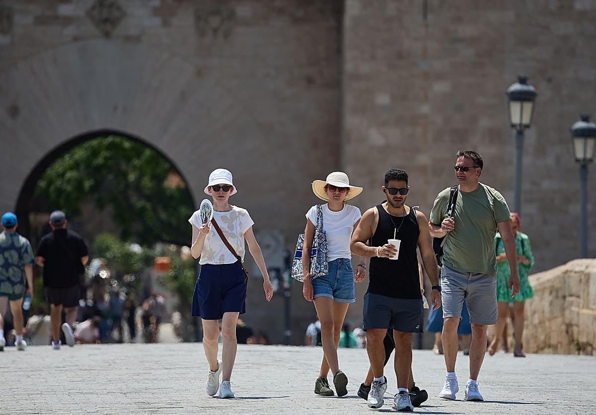 Turistas pasean por Valencia equipados con sombreros y abanicos para combatir el calor.