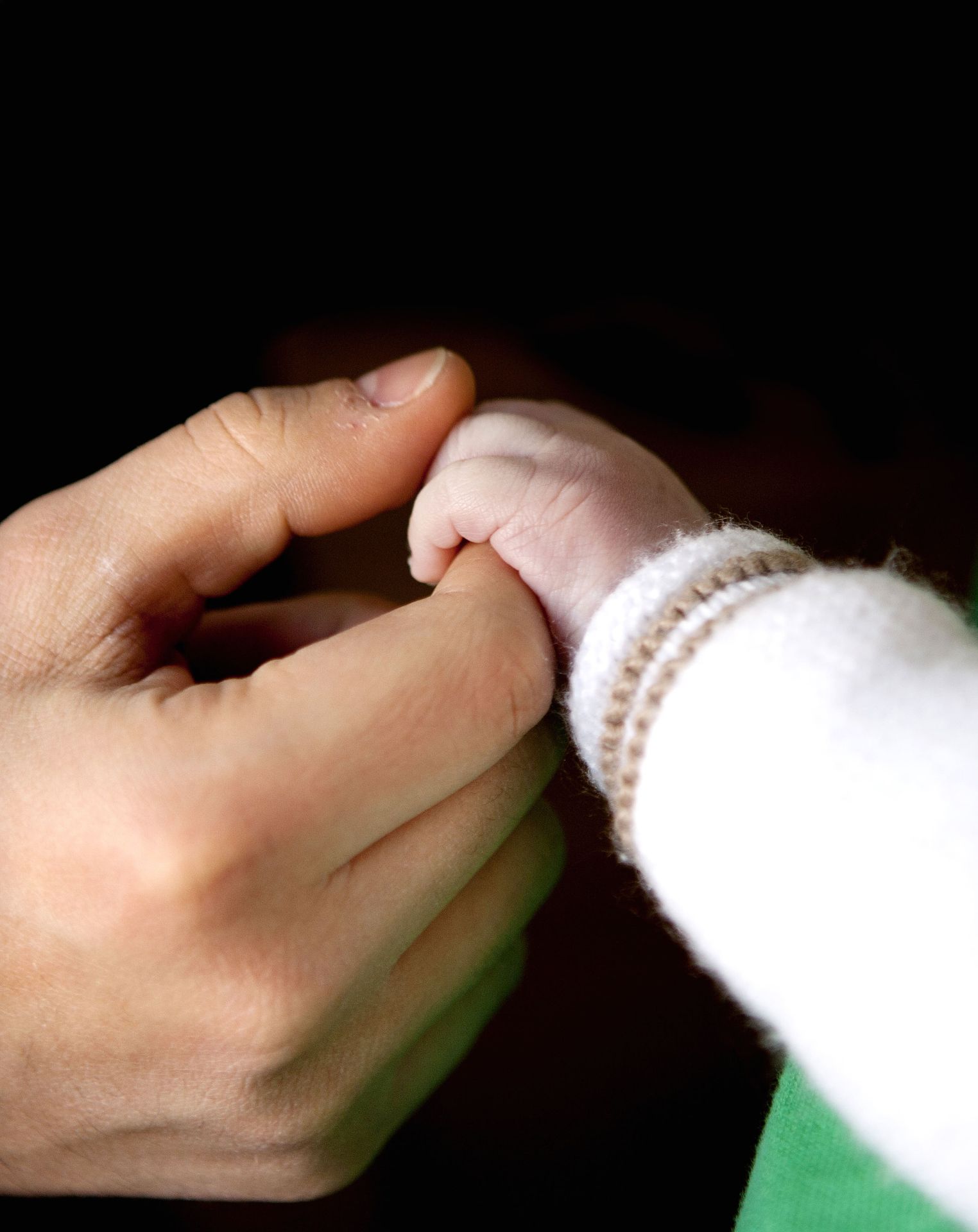 Una mano adulta sosteniendo la mano de una bebé