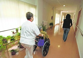 Una celadora traslada a una mujer en una residencia.