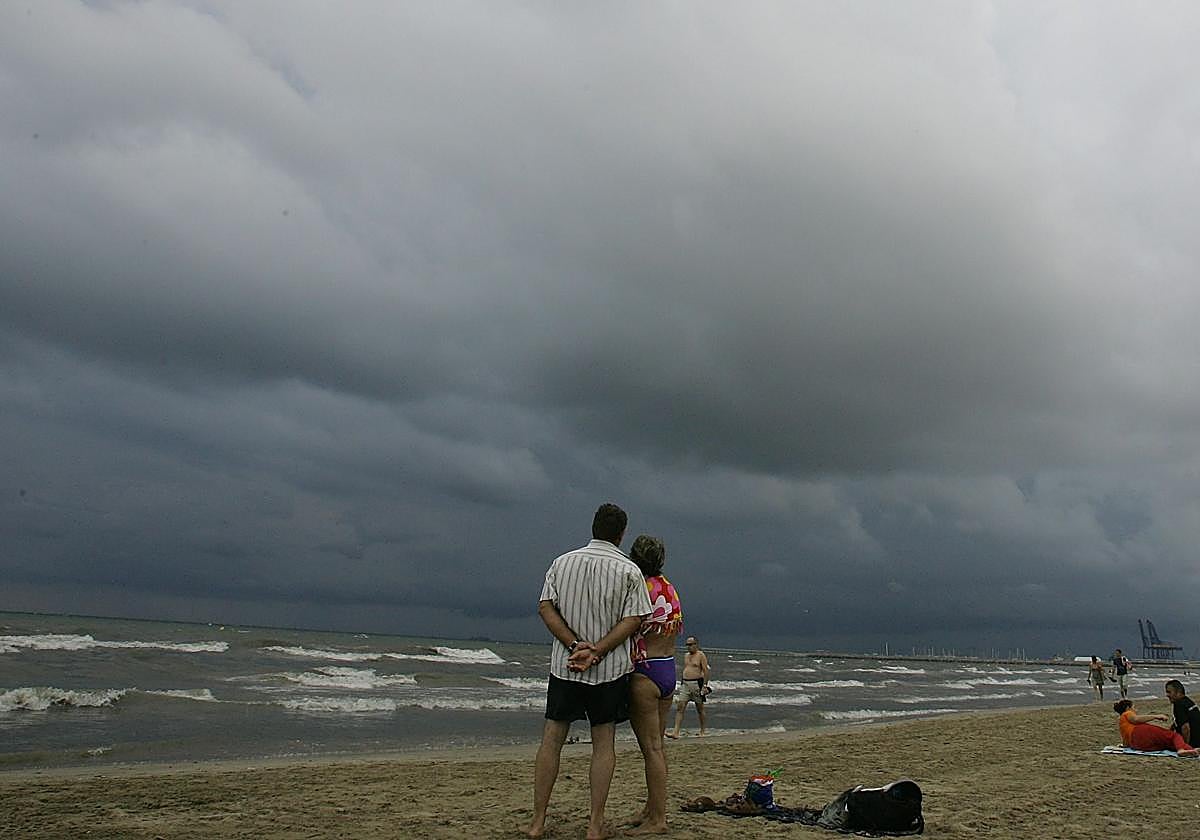 Una pareja visualiza el cielo nublado de Valencia en la Malvarrosa. Imagen de archivo.