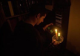 Un hombre se alumbra con unas velas.