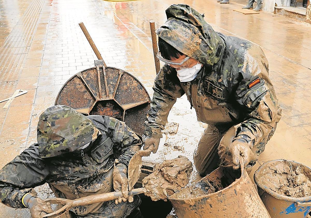 Dos militares del Ejército de Tierra desatascan una alcantarilla en Paiporta, pocos días después de la riada.