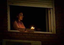 Una mujer se alumbra con una vela.