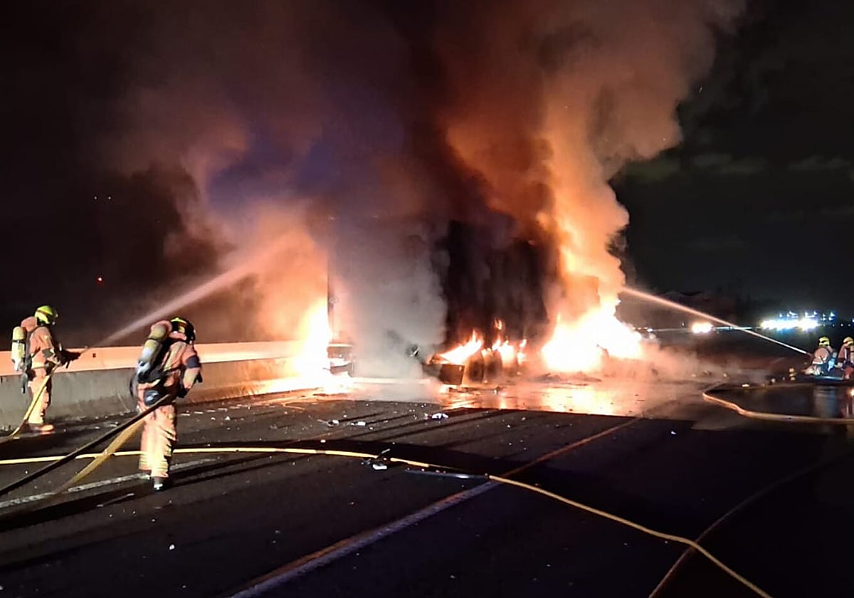 Los bomberos arrojan agua sobre el fuego que destruyó uno de los camiones en la A-7.