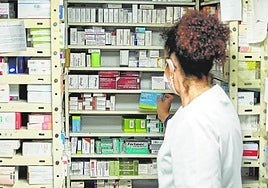 Una farmacéutica muestra huecos vacíos en sus estantes.