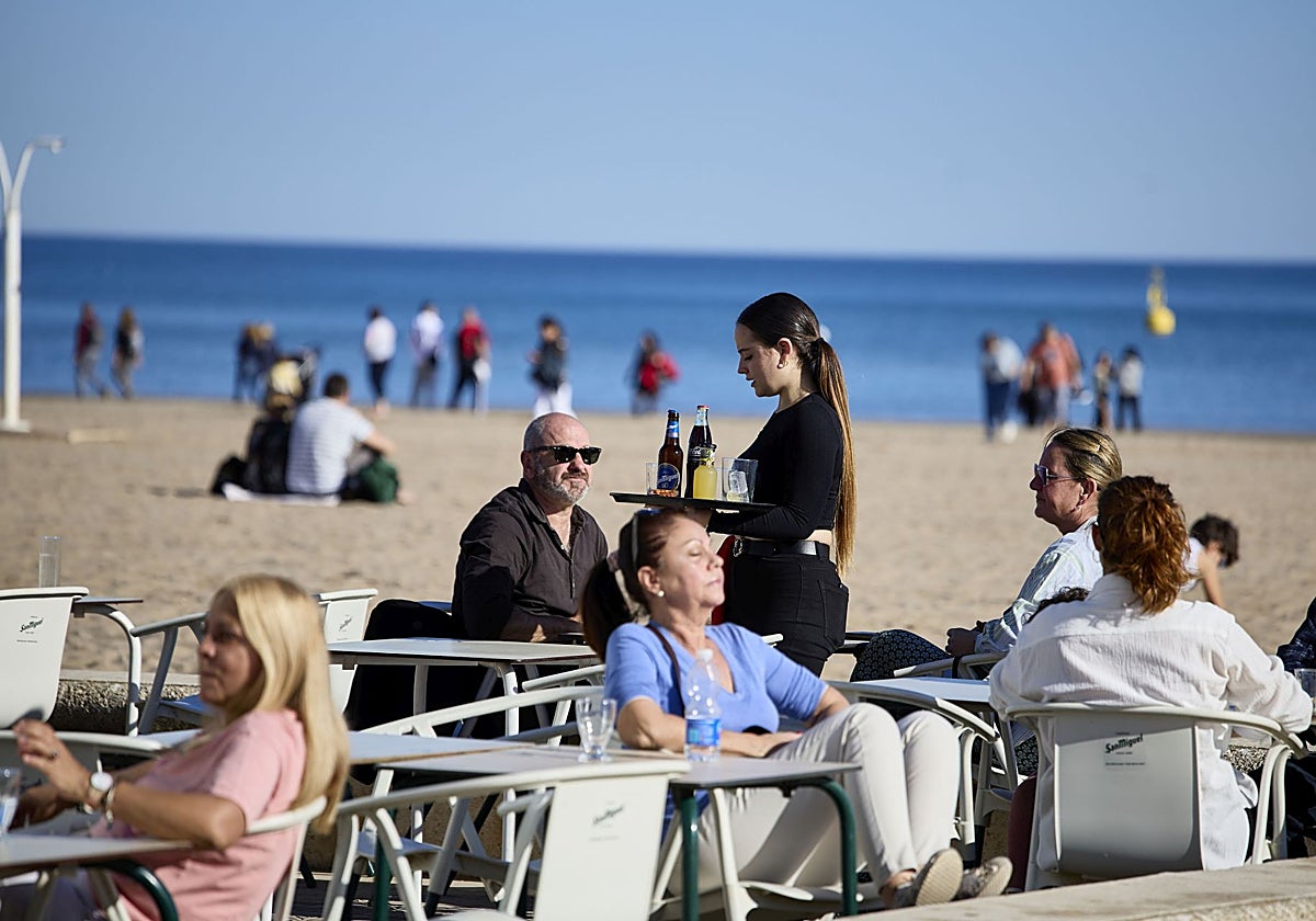 Una camarera sirve en una terraza de la playa de Valencia.