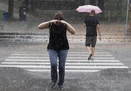 Dos personas se protegen de la lluvia en verano, en una imagen de archivo.