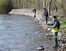 Tres pescadores lanzan la caña en un río.