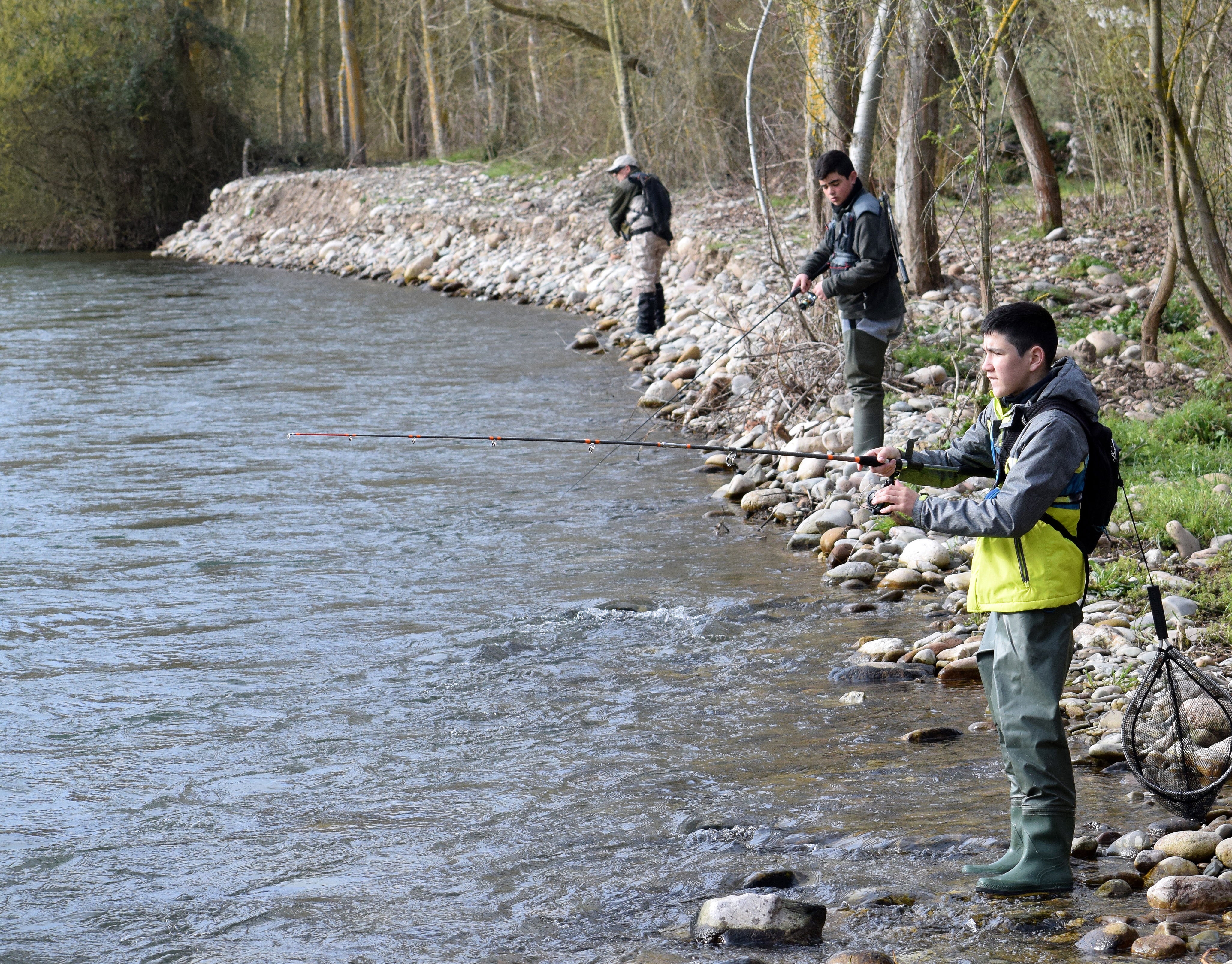 Tres pescadores lanzan la caña en un río.