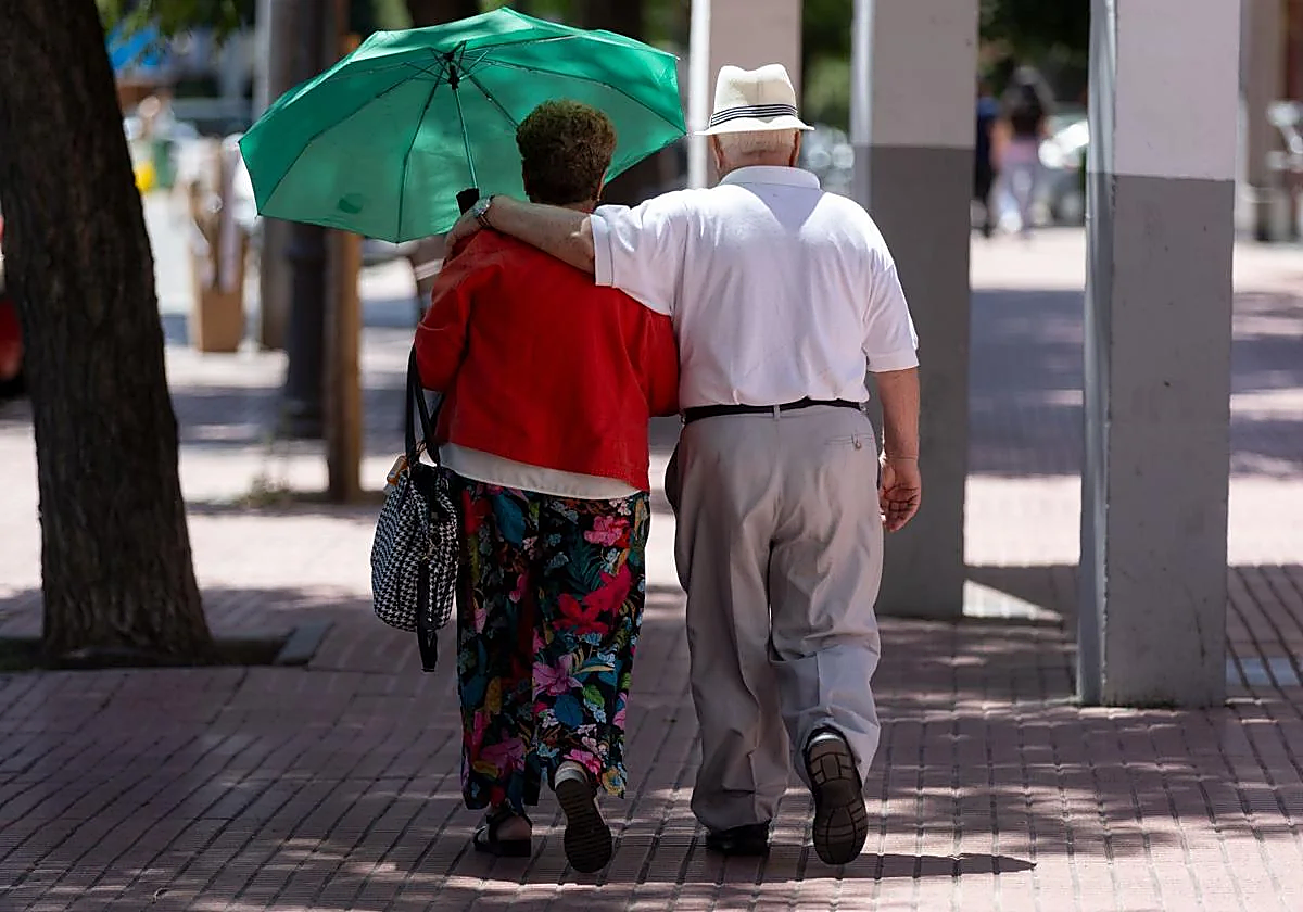 Una pareja de personas mayores pasea por un parque.