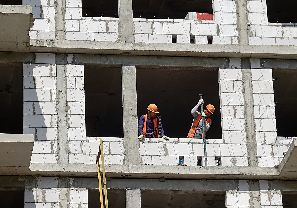 Dos obreros trabajan en la construcción de un edificio.