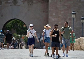 Turistas pasean por Valencia equipados con sombreros y abanicos para combatir el calor.
