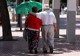 Una pareja de personas mayores pasea por un parque.