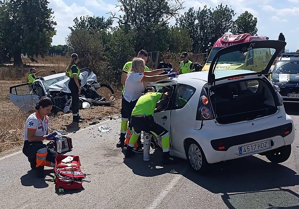 Los sanitarios y guardias civiles asisten a los dos conductores heridos tras el choque frontal.
