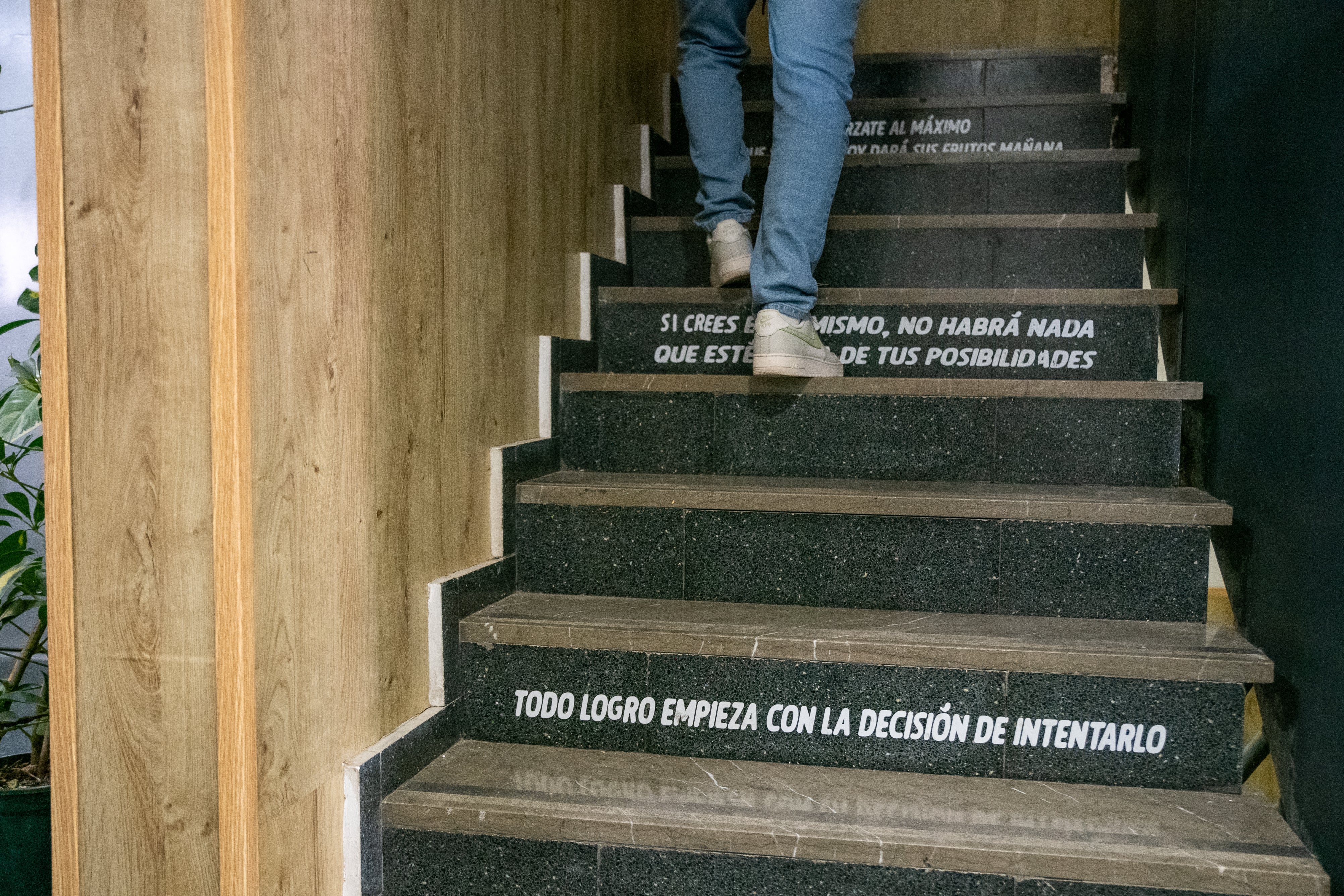 Un joven camina por una escalera con frases motivadoras en los escalones.
