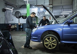 Dos mecánicos trabajan en un taller de automoción.