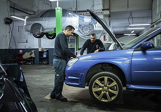Dos mecánicos trabajan en un taller de automoción.