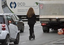 Una mujer circula con patinete electrico por el centro de una ciudad.
