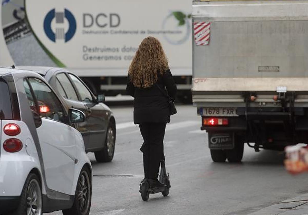 Una mujer circula con patinete electrico por el centro de una ciudad.