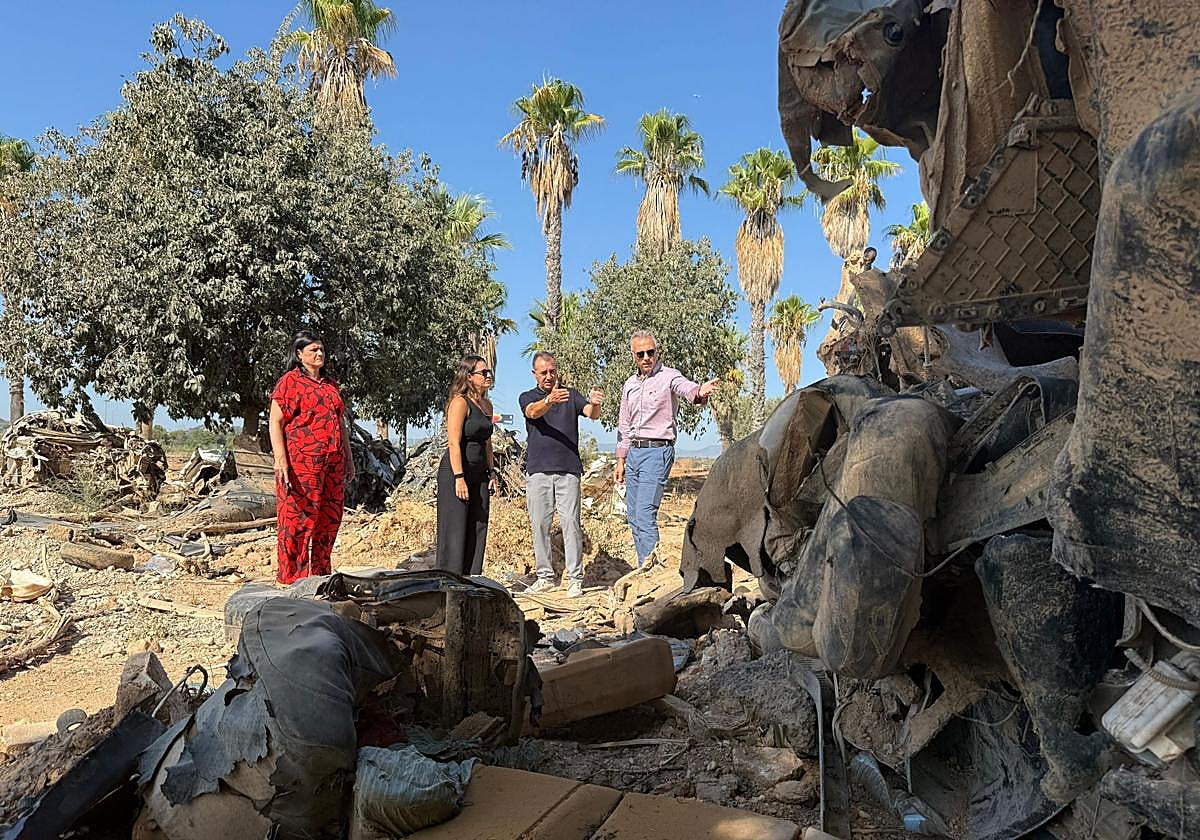 El alcalde Raga señala a la comisionada restos de vehículos pendientes de desguace en un solar junto a la A3.