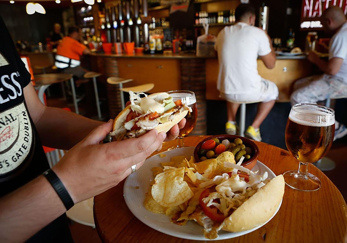 Un hombre consume bebidas y tapas en un bar, imagen de archivo.