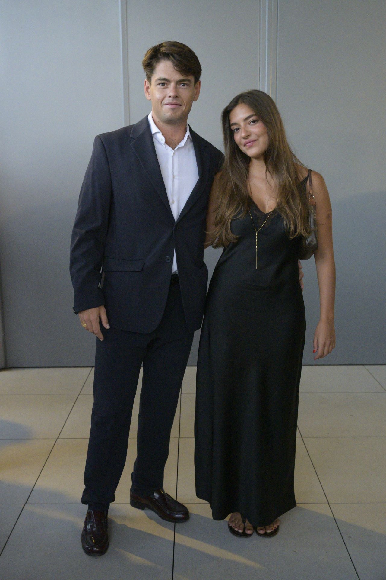 Gonzalo Ferrando luce un traje azul marino de Zara combinado con una camisa blanca y Marta Martí un vestido lencero de Massimo Dutti y un colgante de Singularu.