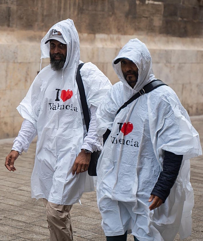 Imagen secundaria 2 - Vehículos estacionados en el puente de Castellar-Oliveral para prevenir que sean arrastrados. Estado del barranco de la Salera a la altura de Aldaia y dos hombres se cubren con chubasqueros en Valencia.