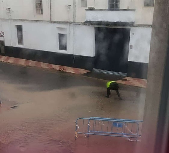 Un agente retirando un imbornal para facilitar la salida del agua.
