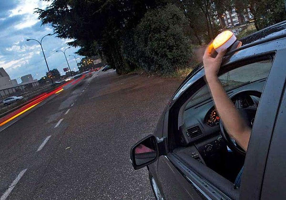 Un conductor coloca una baliza V16 en la parte superior de su vehículo.