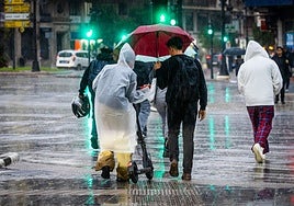 Un grupo de personas caminan bajo la lluvia en Valencia.