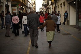 Pareja de pensionistas pasea por una calle peatonal.