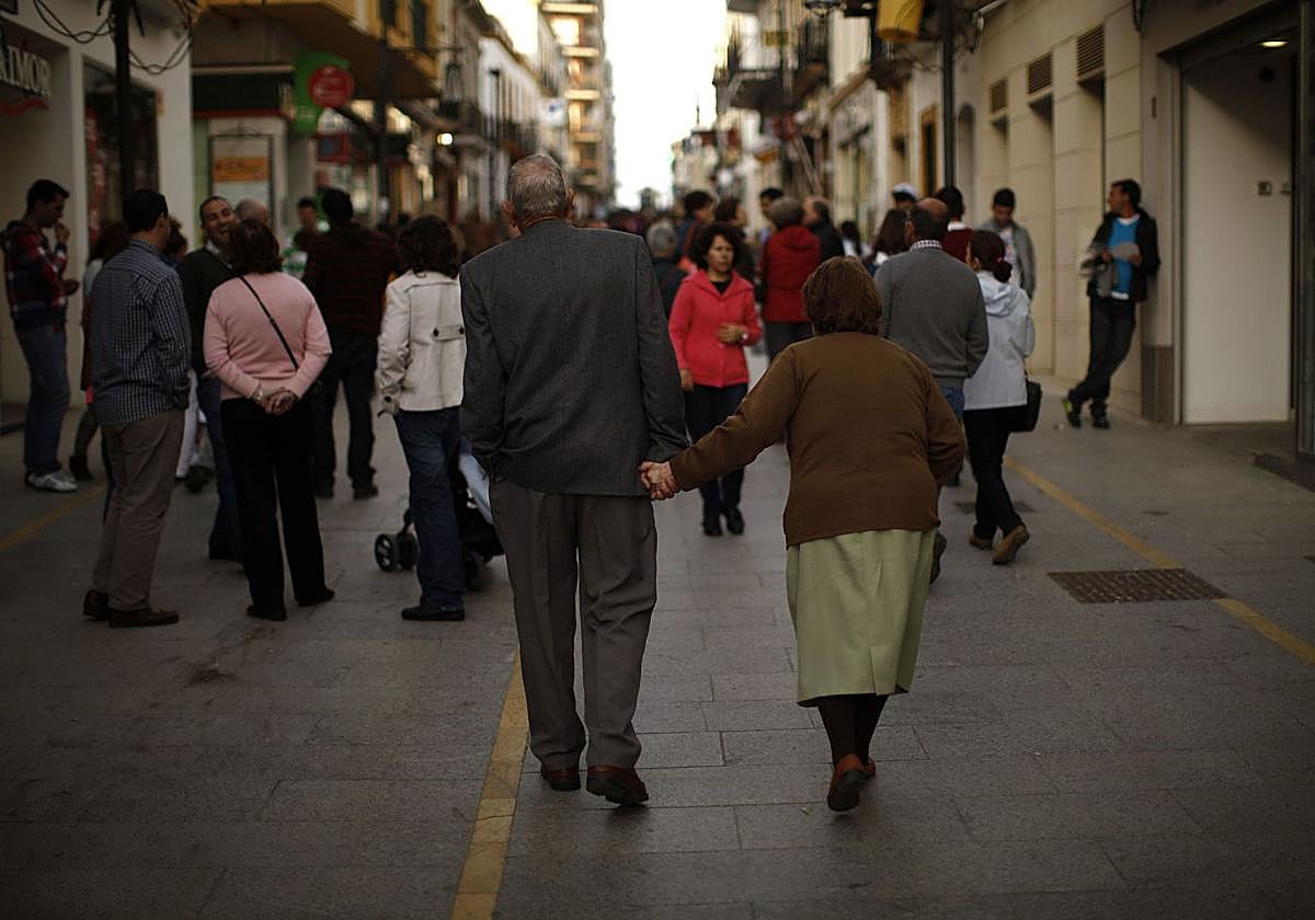 Pareja de pensionistas pasea por una calle peatonal.