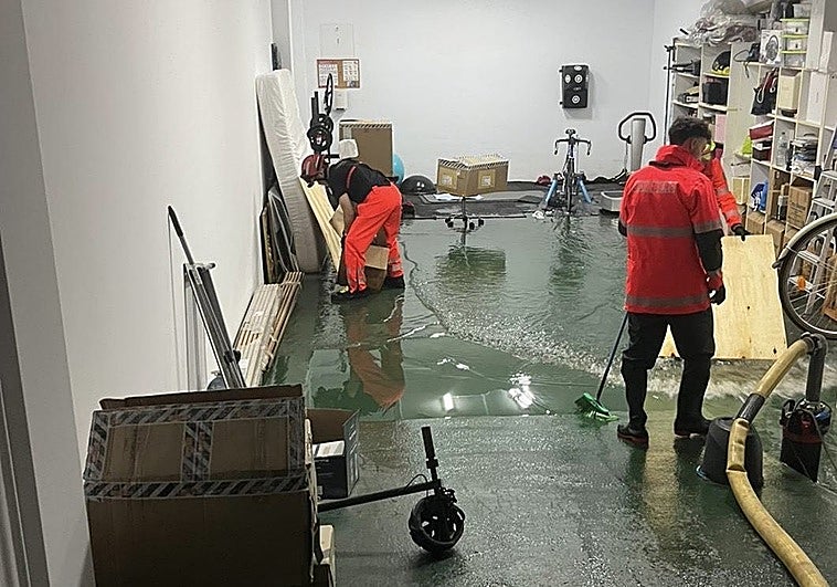 Bomberos trabajan achicando agua en uno de los garajes inundados en Alcàsser.