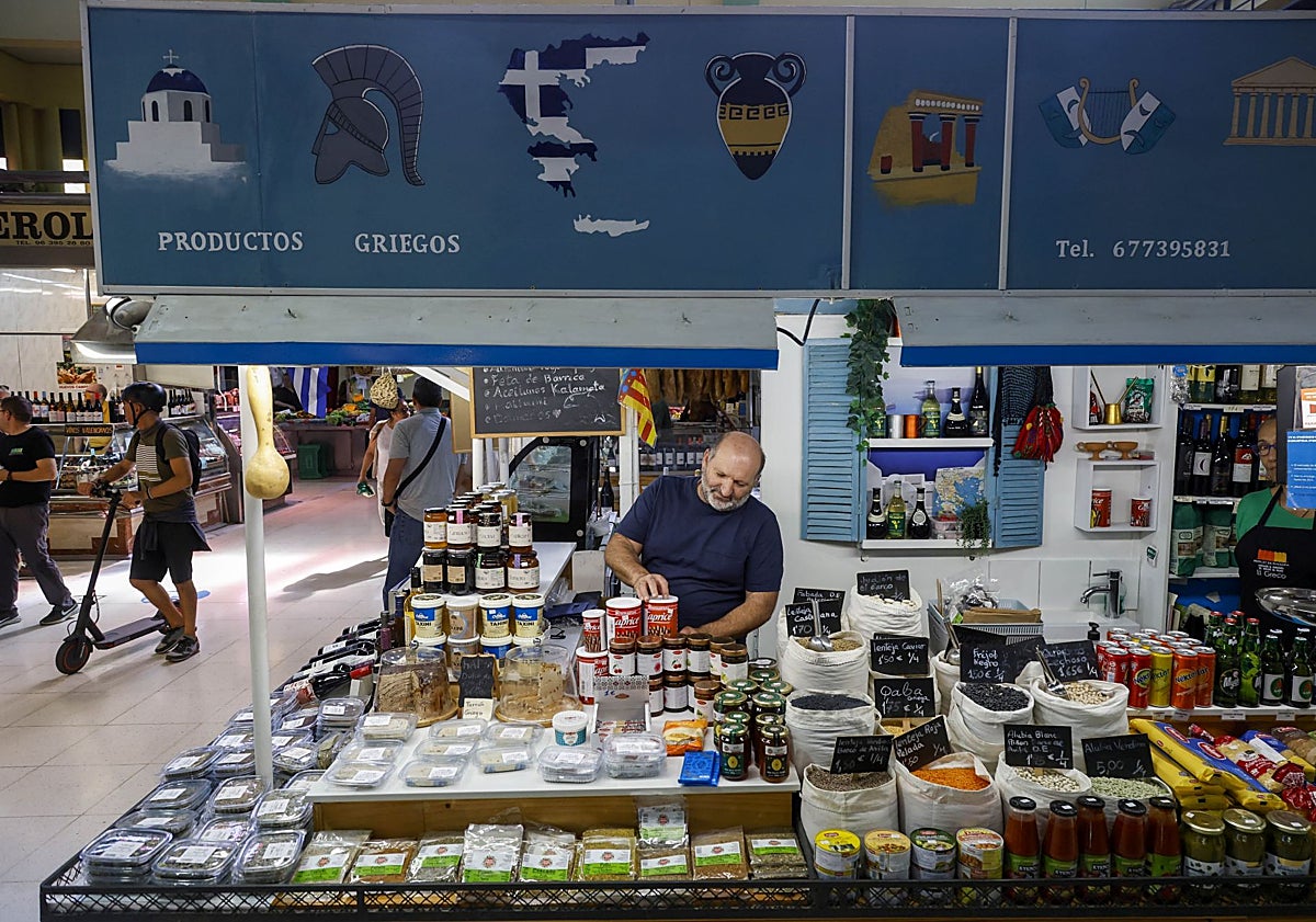Imagen principal - Parada de productos griegos de Carmen Bernat y Dimitris Vamvakas; Carlo Castellano con su puesto de productos italianos, en el mercado de Ruzafa, y Nela Daza y Gregorio Pisciotta, en su puesto del mercado de Castilla.