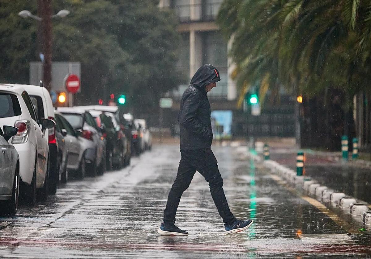 Un hombre pasea bajo la lluvia en Valencia.