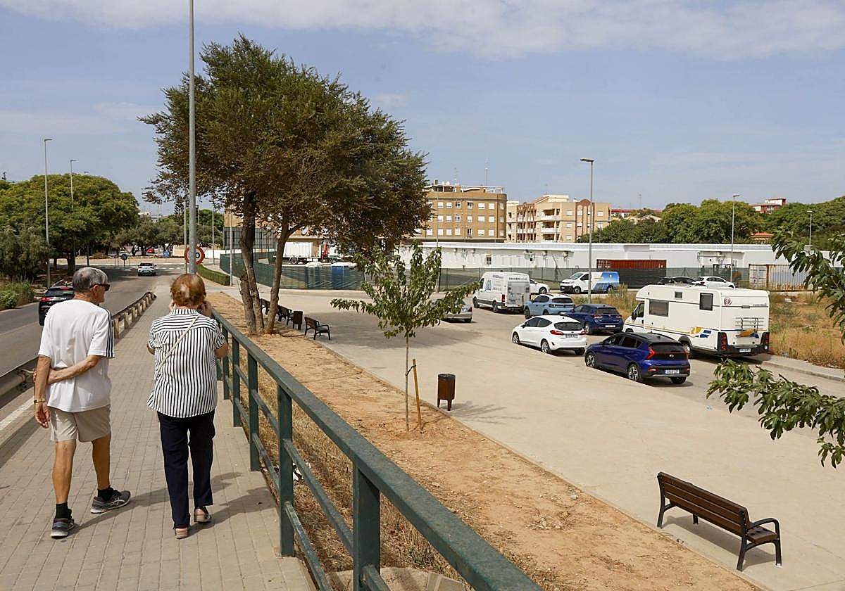 Dos viandantes pasean por un jardín de Alfafar.