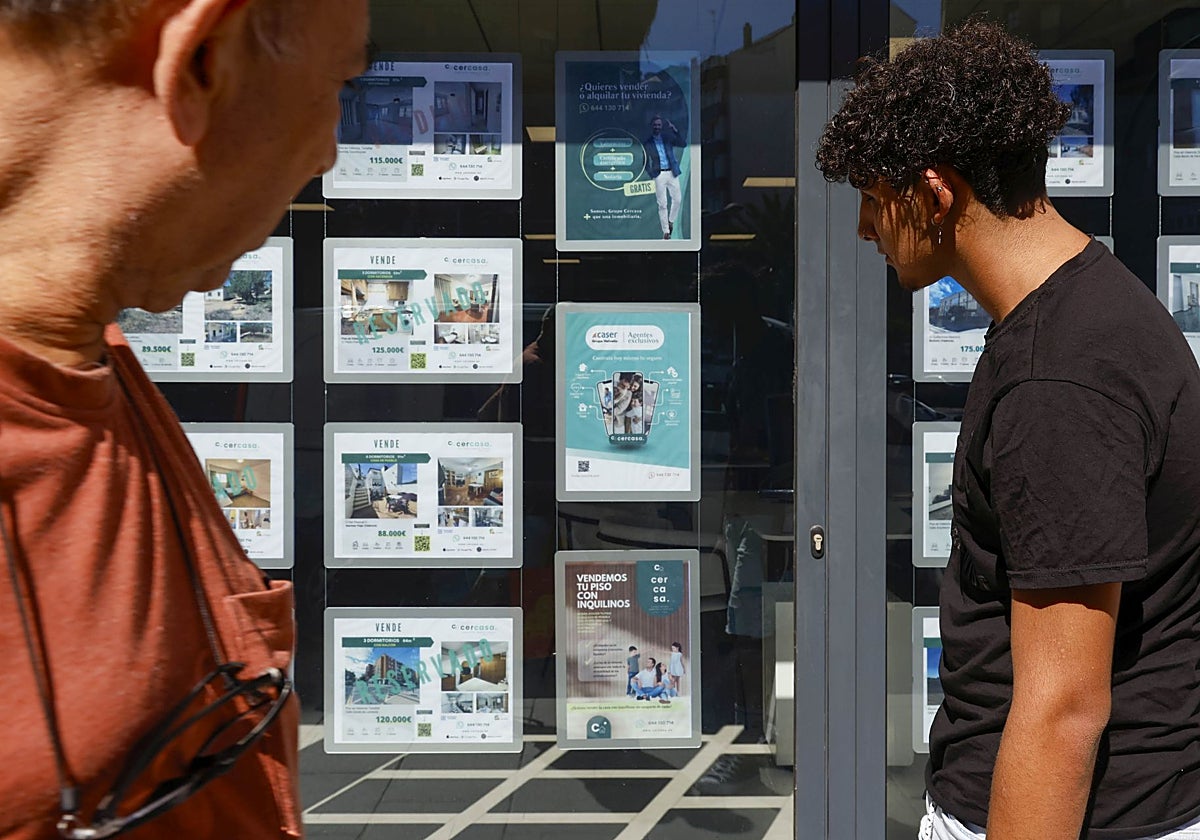 Dos personas observan los precios en una inmobiliaria de Valencia
