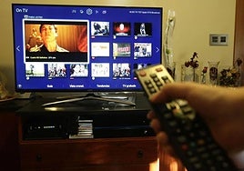 Una persona ordena los canales de su televisor con un mando a distancia.