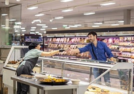 Una dependienta entrega un plato preparado a un cliente.